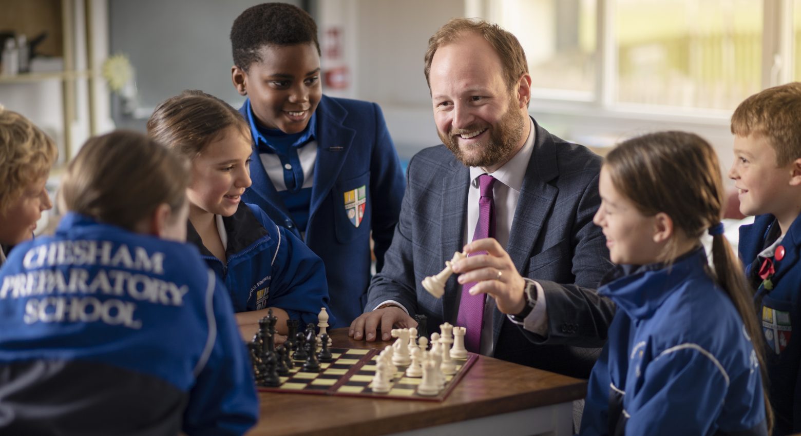 students playing chess with their teacher