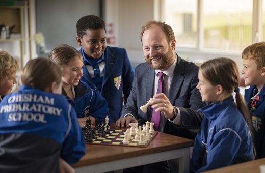 students playing chess with their teacher